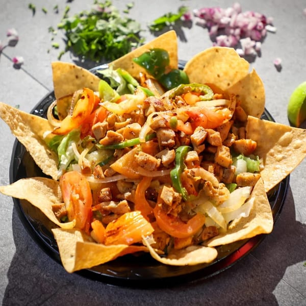 Taco Plus Mexican Grub's chicken fajita salad with tortilla chips, tomatoes, onions, and peppers.