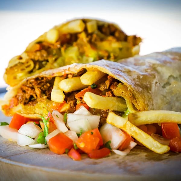 Two large burritos filled with meat and french fries, served with a side of pico de gallo.